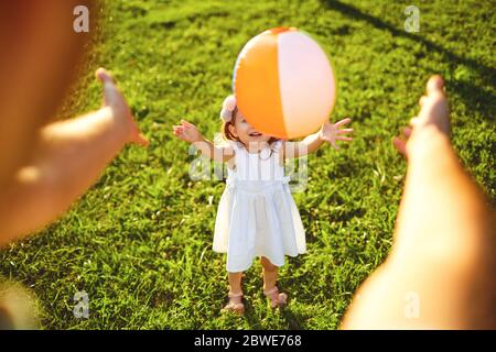 Fröhliche Familienspaziergänge auf dem Gras im Sommerpark. Mutter Vater und Kinder, die in der Natur spielen. Kinderschutztag. Stockfoto