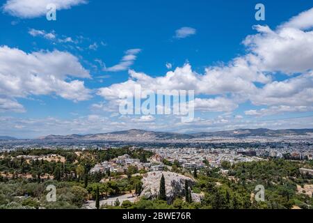 Athen Stadtbild und Aropag Hügel gegen blauen bewölkten Himmel in einem Frühlingstag. Luftaufnahme vom Akropolis-Hügel. Attica, Griechenland Stockfoto