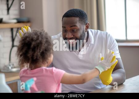 afroamerikanischer bärtiger Mann, der beim Spielen mit seinem Kind lustig aussieht Stockfoto