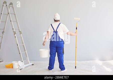 Malermalerei. Lustiger männlicher Maler mit einem Rollschuh stehend malt im Hintergrund. Stockfoto