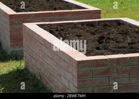 Ein moderner Gemüsegarten mit erhöhten Briks Betten. Bereit zum Pflanzen Stockfoto