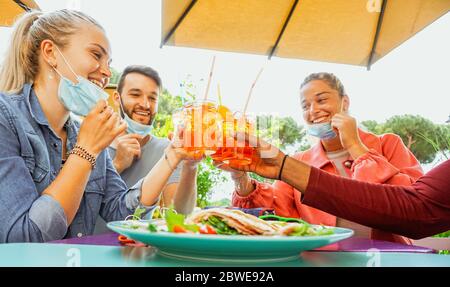 Freunde trinken Coktail und essen Snack Tapas in einer Restaurant-Bar draußen an Sommertagen mit Gesichtsmaske auf vor Coronavirus geschützt werden - glücklich Stockfoto