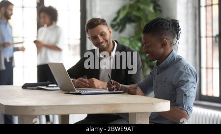 Zufriedener afroamerikanischer Kunde, der den Vertrag bei einem Treffen mit dem Manager unterzeichnet Stockfoto