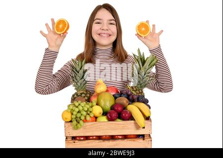 Mädchen mit Orangen und Obst in Holzkiste Stockfoto