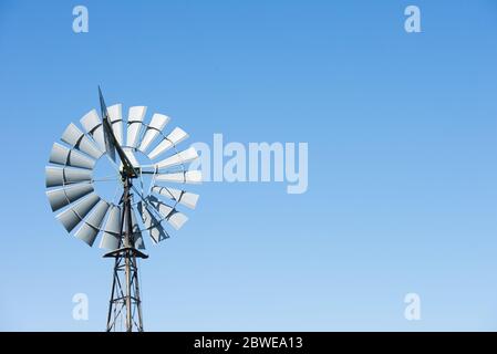 Alte Vintage Windmühle oder Wasserpumpe im Outback Australien, isoliert am blauen Himmel, Kopierraum. Stockfoto