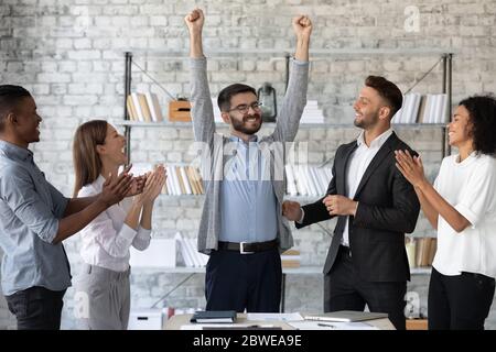 Diverse Mitarbeiter gratulieren erfolgreichen Kollegen mit Beförderung Stockfoto