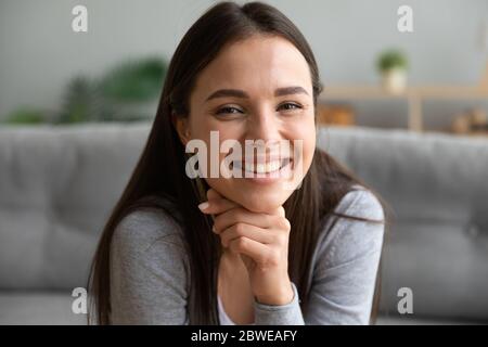 Schöne junge Frau sitzen auf Couch lächelt schaut Kamera Stockfoto