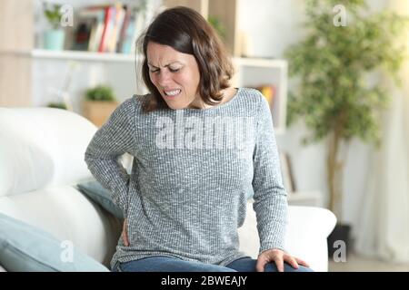 Frau im mittleren Alter in Schmerzen leiden Rückenschmerzen stting auf einer Couch zu Hause Stockfoto