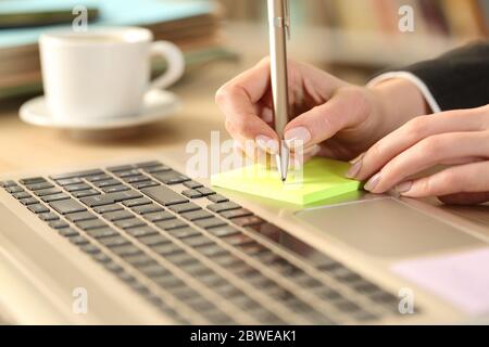 Nahaufnahme der Unternehmerin Hände schriftlich Erinnerung auf Post-Note auf einem Schreibtisch zu Hause Stockfoto