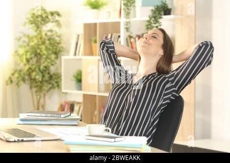 Zufriedene Unternehmerin, die sich auf einem Schreibtisch im Homeoffice entspannt Stockfoto