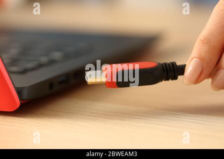 Nahaufnahme der Hände einer Frau, die HDMI-Kabel an einen Laptop auf einem Schreibtisch anschließen Stockfoto