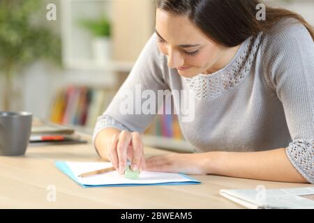Glückliche Frau Radieren Bleistiftmarken auf Papier mit Gummi sitzen auf einem Schreibtisch zu Hause Stockfoto
