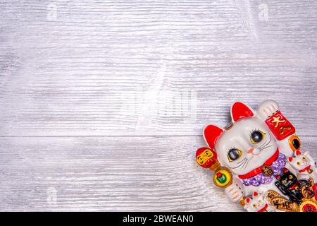 Japanisches Symbol des Glücks Maneki Neko Katze auf silbernem Holzhintergrund. Draufsicht Stockfoto