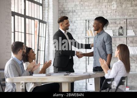 Lächelnder Manager gratuliert afroamerikanischen Mitarbeiter, schüttelt die Hände Stockfoto