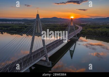 Budapest, Hungary - Luftaufnahme der Megyeri Hängebrücke bei Sonnenuntergang mit schönem blauen und goldenen Himmel und Wolken und untergehende Sonne hinter Stockfoto