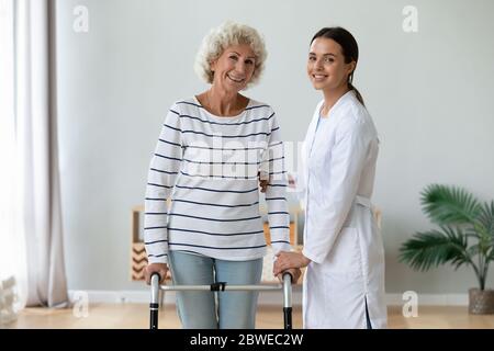 Ältere Frau mit Rollator fühlt sich nach der Therapie mit Physiotherapeuten zufrieden Stockfoto