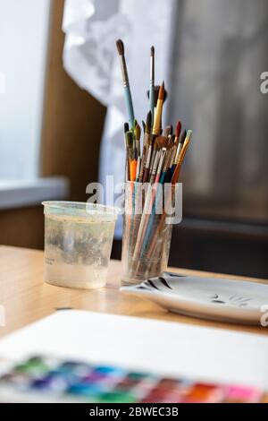 Kunstpinsel zum Malen in einer Glasschale auf dem Desktop. Stockfoto