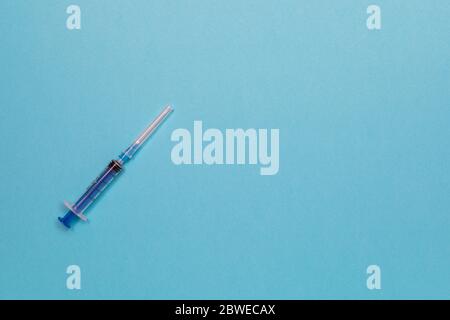 Spritze zur Injektion mit einer Nadel auf blauem Hintergrund. Draufsicht mit Kopierfläche, flachem Lay. Stockfoto