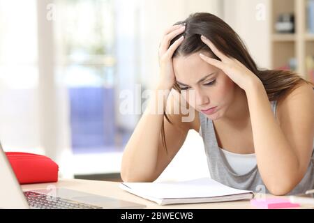 Überwältigte Studentin Frau studieren Auswendiglernen Notizen sitzen auf einem Schreibtisch zu Hause Stockfoto