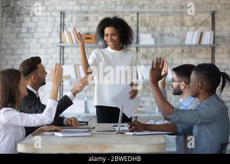 Lächeln verschiedene Geschäftsleute Hände heben, Abstimmung bei Corporate Meeting Stockfoto