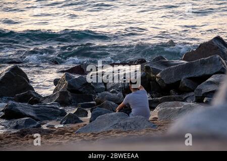 Fotograf am Strand die Kamera aufsetzen und auf einen guten Moment für die Fotografie warten Stockfoto