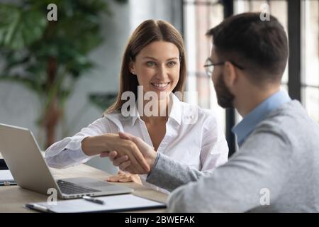 Lächelnde Geschäftsfrau schüttelt Kollegen die Hand, arbeitet am Projekt zusammen Stockfoto