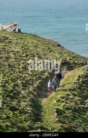 Eine junge Familie, die einen Spaziergang entlang des Küstenpfades und den Blick aufs Meer von Pitre Point East in Newquay in Cornwall genießt. Stockfoto