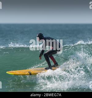 Ein Surfer, der ein Longboard beim Fistral in Newquay in Cornwall benutzt. Stockfoto