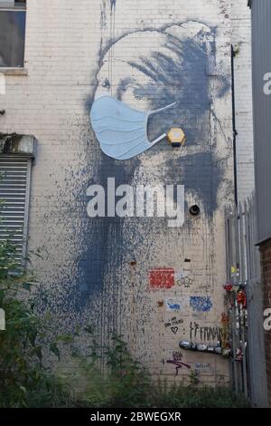 Banksy Graffiti das Mädchen mit dem durchbohrten Trommelfell mit blauer Gesichtsmaske (Covid-19). Albion Dockyard, Hanover Place, Bristol Stockfoto