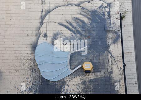 Banksy Graffiti das Mädchen mit dem durchbohrten Trommelfell mit blauer Gesichtsmaske (Covid-19). Albion Dockyard, Hanover Place, Bristol Stockfoto