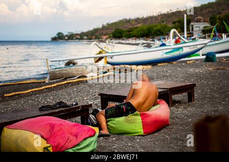 BALI, INDONESIEN - 01. Dezember 2019: Touristen entspannen in einem typischen kleinen Black Sand Beach Cafe auf Bali Stockfoto