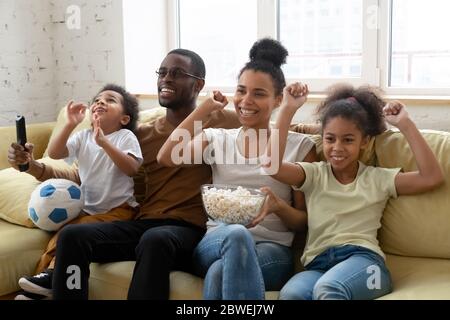Afrikanische Familien-Fußballfans beobachten ein Spiel auf dem Sofa im Haus Stockfoto