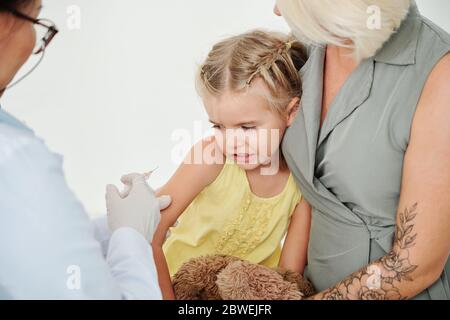 Erschrockenes kleines Mädchen, das in der Klinik Windpocken-Impfungen erhält Stockfoto