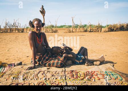 Omorate, Omo Valley, Äthiopien - 11. Mai 2019: Frau aus dem afrikanischen Stamm Dasanesh mit Baby bietet handgemachte Souvenirs. Daasanach sind Cushitic Ethns Stockfoto