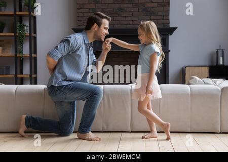 Liebevoller Vater kniet küssen kleine Tochter Hand Stockfoto