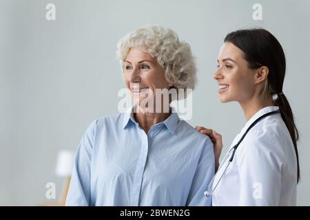 Die Krankenschwester legt Hand auf Schulter eines älteren Patienten, der Pflege zeigt Stockfoto