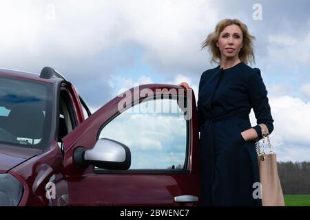 Business-Frau mit ihrem Auto in einem Wald in der Nähe stehenden Stockfoto