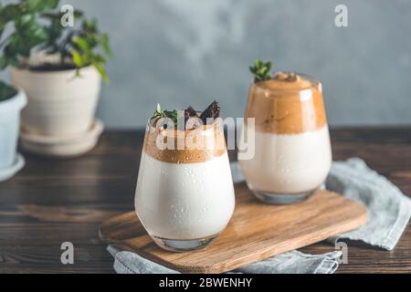 Zwei Gläser mit Wassertropfen von Dalgona schaumig Kaffee Trend koreanischen Drink Latte Espresso mit Kaffeeschaum, von Thymian und dunkler Schokolade dekoriert. Dunkel Stockfoto