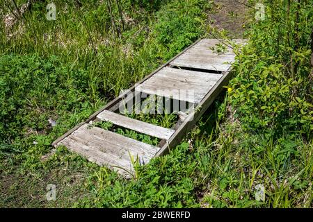 Kleine Holzbrücke mit fehlenden Brettern Stockfoto