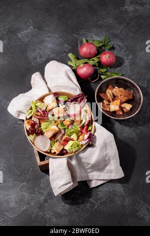 Traditioneller nahöstlicher Fattoush-Salat mit Pita-Brot, frischem Gemüse und Zitronensumac-Dressing auf dunkelgrauem Hintergrund Draufsicht Stockfoto