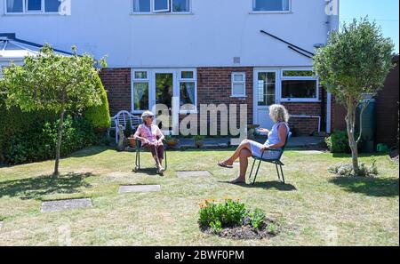 Rustington West Sussex UK 1. Juni 2020 - Jean Russell (links) aus Rustington bei Littlehampton plaudert und scherzt mit ihrer Tochter Jennie im Garten, nachdem sie sich zum ersten Mal seit der Sperrung im März während der COVID-19-Pandemie wiederfand.: Credit Simon Dack / Alamy Live News Stockfoto