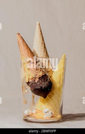 Geometrische Zusammensetzung von verschiedenen geschmolzenen Eis Waffel-Kegel in Glas auf beigefarbenen Pastell Hintergrund.Sommer kreative Konzept Stockfoto