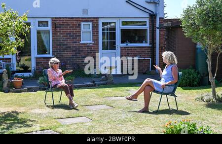 Rustington West Sussex UK 1. Juni 2020 - Jean Russell (links) aus Rustington bei Littlehampton plaudert und scherzt mit ihrer Tochter Jennie im Garten, nachdem sie sich zum ersten Mal seit der Sperrung im März während der COVID-19-Pandemie wiederfand.: Credit Simon Dack / Alamy Live News Stockfoto