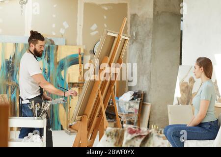 Seitenansicht portrai von männlichen bärtigen Künstler Malerei Porträt der jungen Frau im Studio, kopieren Raum Stockfoto