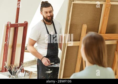 Porträt von fröhlichen bärtigen Künstler Malerei Porträt der jungen Frau im Studio, Kopie Raum Stockfoto