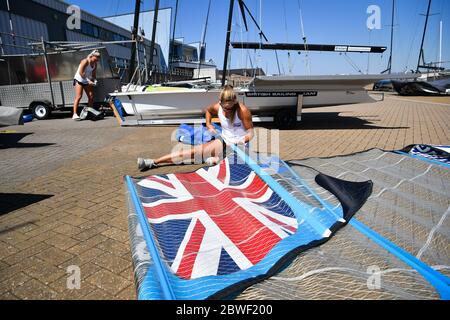 Tokio 2020 Athlet Charlotte Dobson setzt einen Schlagstock in ein Segel, als sie und Teamkollege Saskia Tidey, links, Bereiten Sie ihre 49er FX für eine Trainingseinheit vor, da die Mitglieder des Teams GB bei Weymouth und der Portland National Sailing Academy in Paaren wieder auf dem Wasser trainieren, da die Lockdown-Beschränkungen in England lockern. Stockfoto