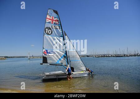 Die 2020-Athleten Saskia Tidey, links, und Charlotte Dobson, rechts, treten mit ihrem 49er FX für eine Trainingseinheit ins Wasser, da Mitglieder des Teams GB bei Weymouth und der Portland National Sailing Academy paarweise wieder auf dem Wasser trainieren, da die Lockdown-Beschränkungen in England lockern. Stockfoto