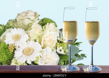 Zwei Gläser Champagner und ein verschwommenes Bouquet weißer Blumen. Stockfoto