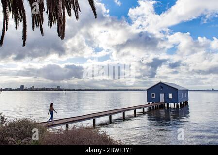 Perth, Nov 2019: Mädchen-Tourist, die auf dem Pier spazieren gehen und auf das berühmte kleine blaue Bootshaus schauen - das Crawley Edge Boatshed am Swan River Stockfoto