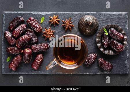 Ramadan Getrocknete Datteln Und Türkischer Tee-Cup Auf Schwarzem Schieferhintergrund, Draufsicht Stockfoto